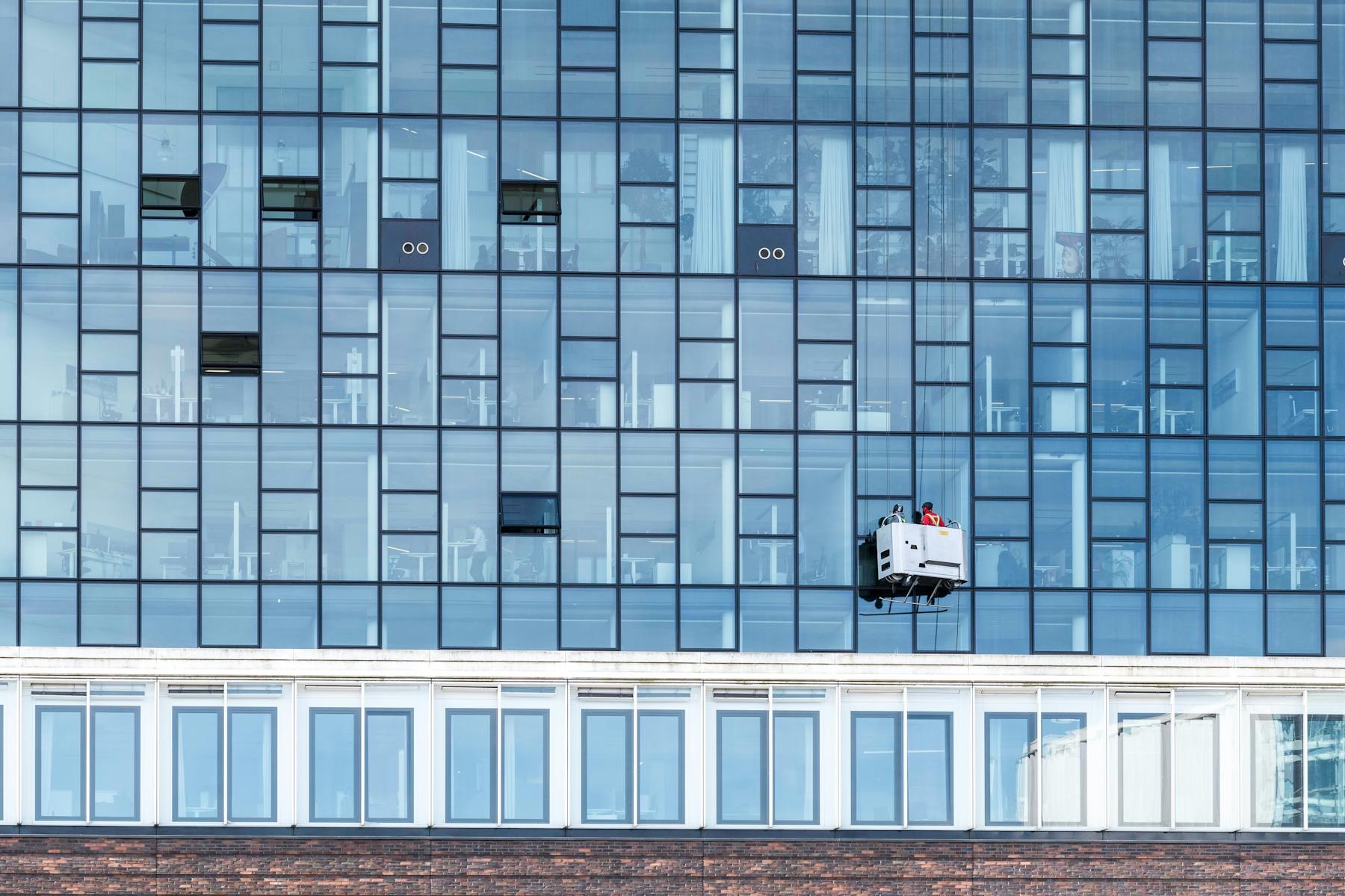 Commercial high-rise facility maintenance — suspended cradle servicing a Texas glass-facade building