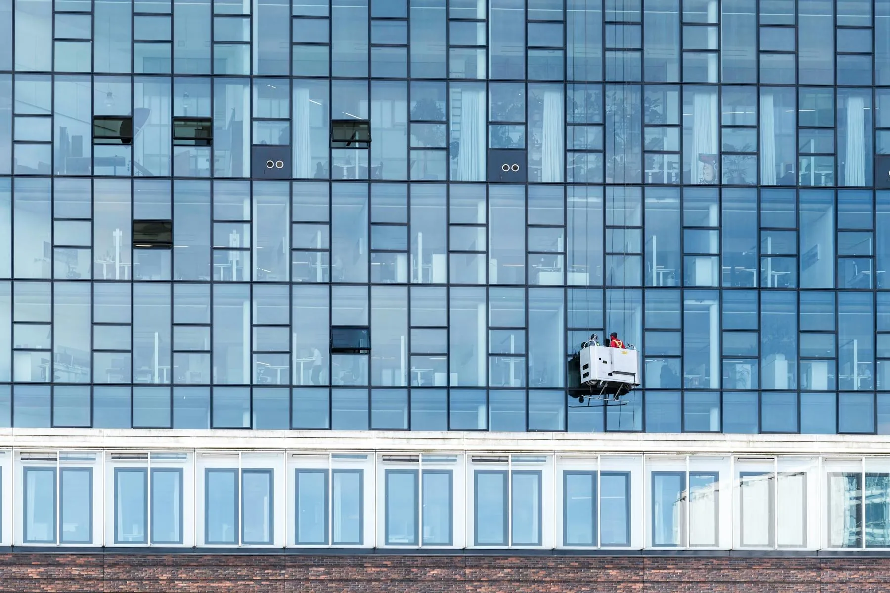 Commercial high-rise facility maintenance — suspended cradle servicing a Texas glass-facade building